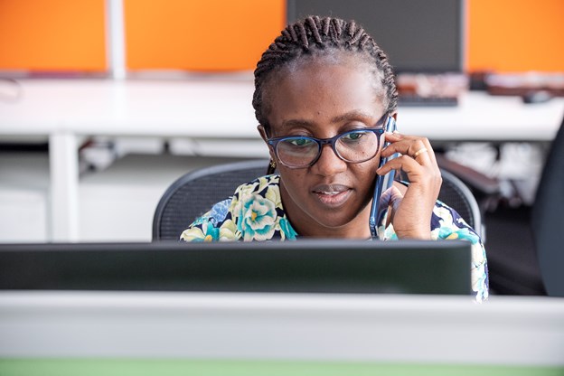 Frau spricht am Telefon und schaut auf dem Computer